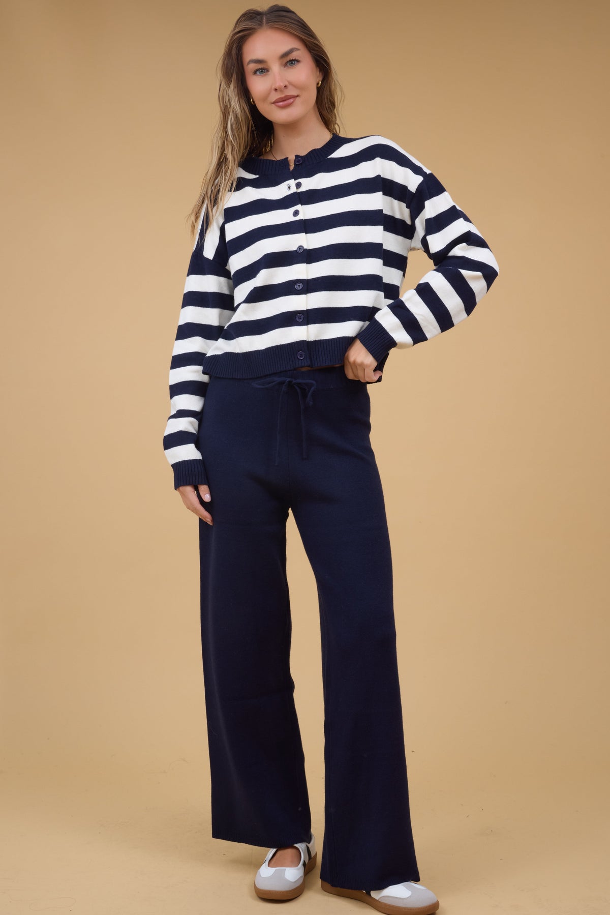 Woman wearing a navy & white stripe button down cardigan and wide leg navy sweater pants.