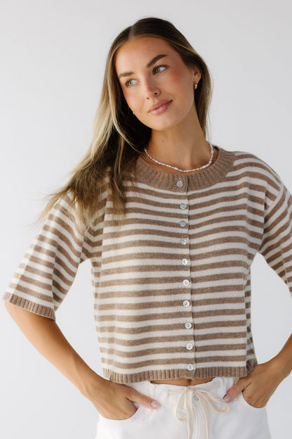 A young woman wearing a modest taupe & cream  stripe cardigan with elbow length sleeves and a wide, ribbed crew neckline.
