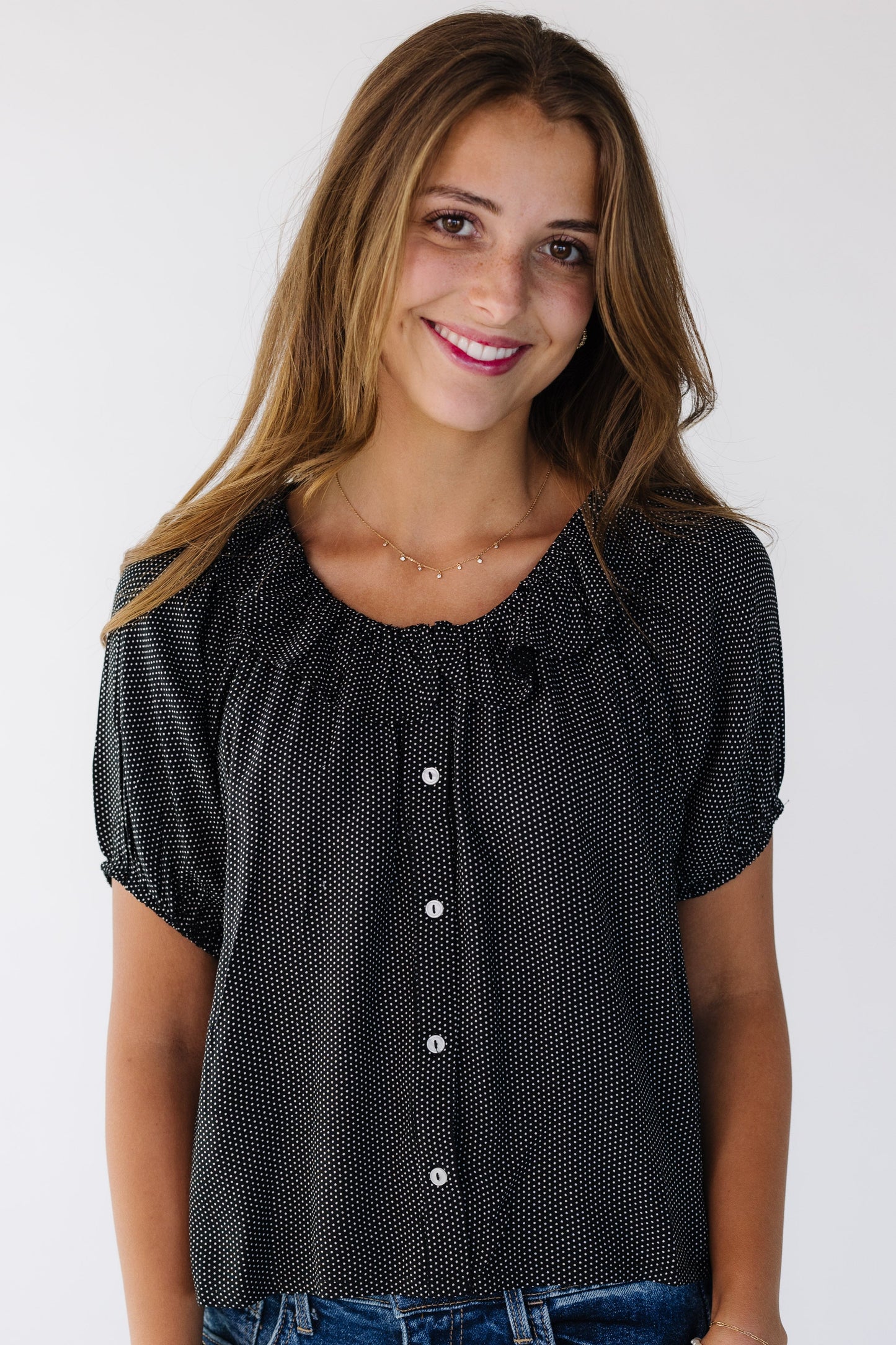 Young woman wearing a modest  black polka dot button down blouse with a round ruffled neckline and puff sleeves.