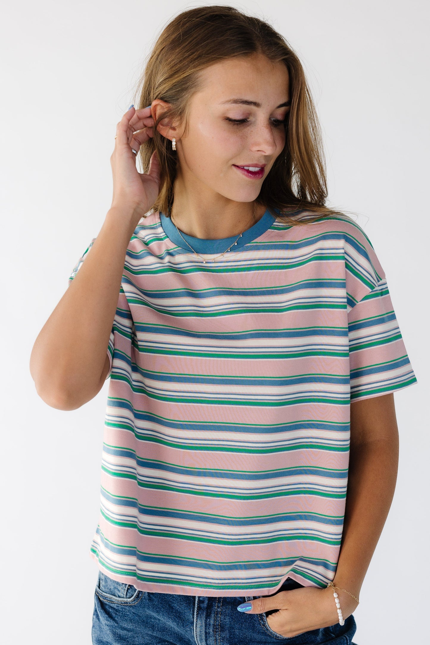 Young women wearing a multi color stripe tee with a crew neckline and short sleeves.