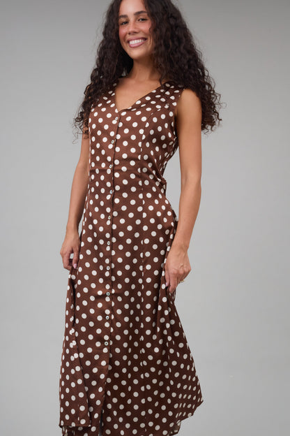 Woman wearing a brown & cream polka dot dress with a V-neckline, Sleeveless, and full skirt.