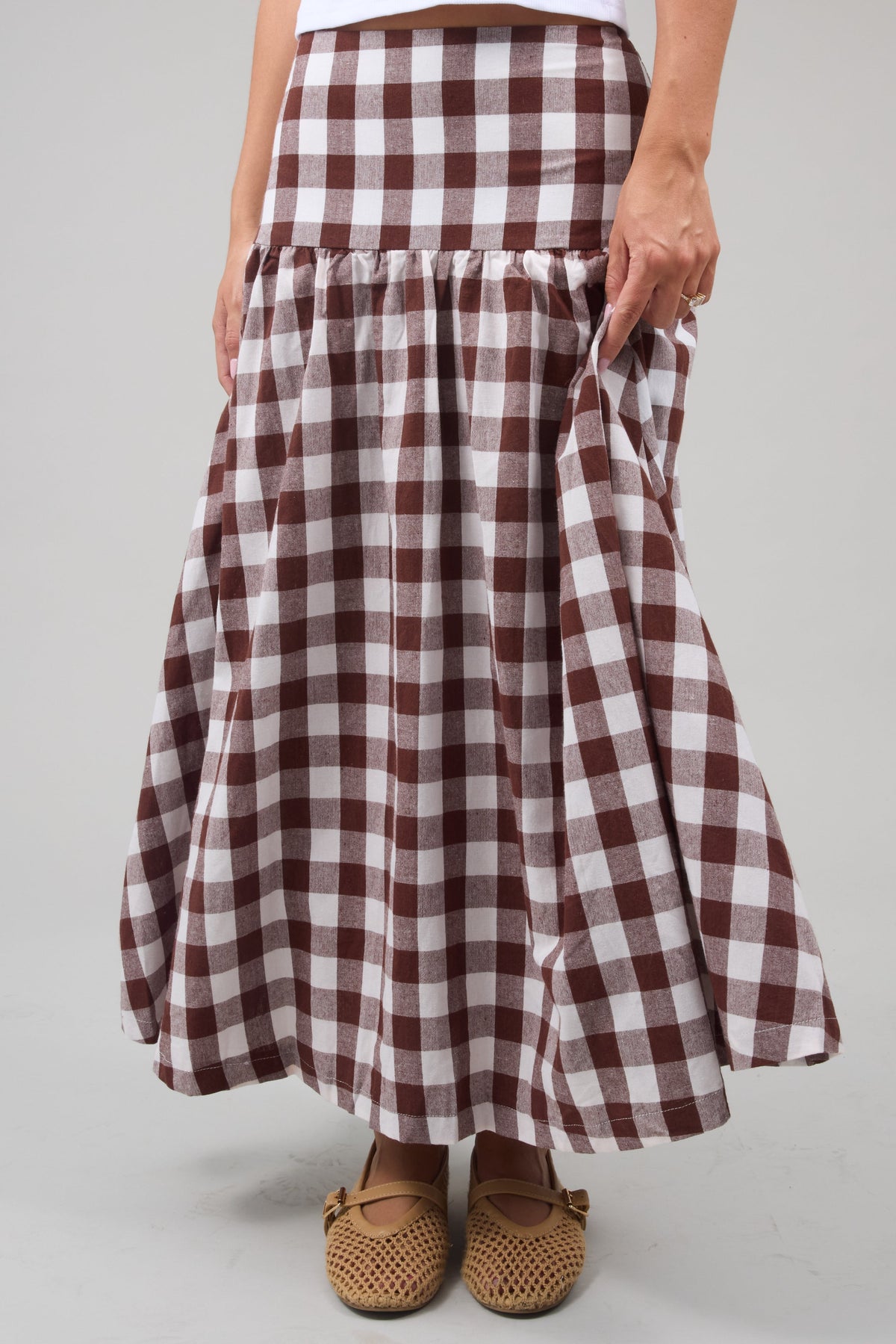 Young woman wearing a modest drop waist midi skirt in a large brown & white gingham.