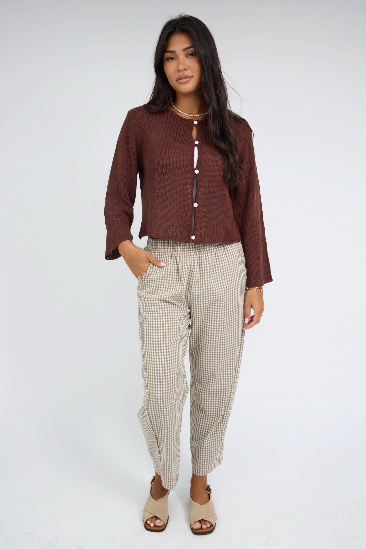 Woman wearing a brown lightweight, long sleeve, button down cardigan.