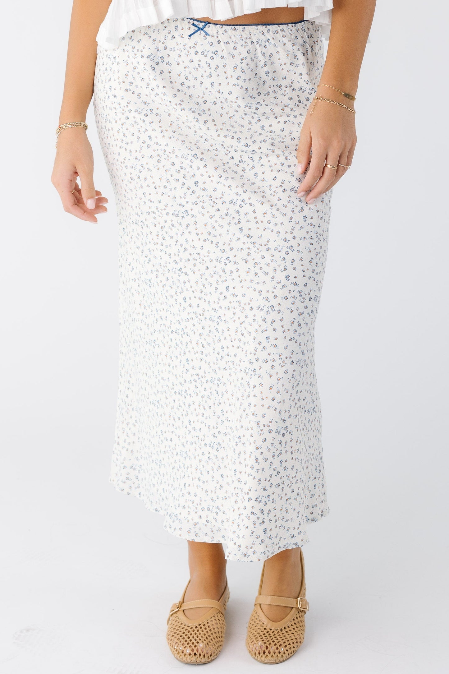 Woman wearing a white A-line midi skirt with blue floral print.