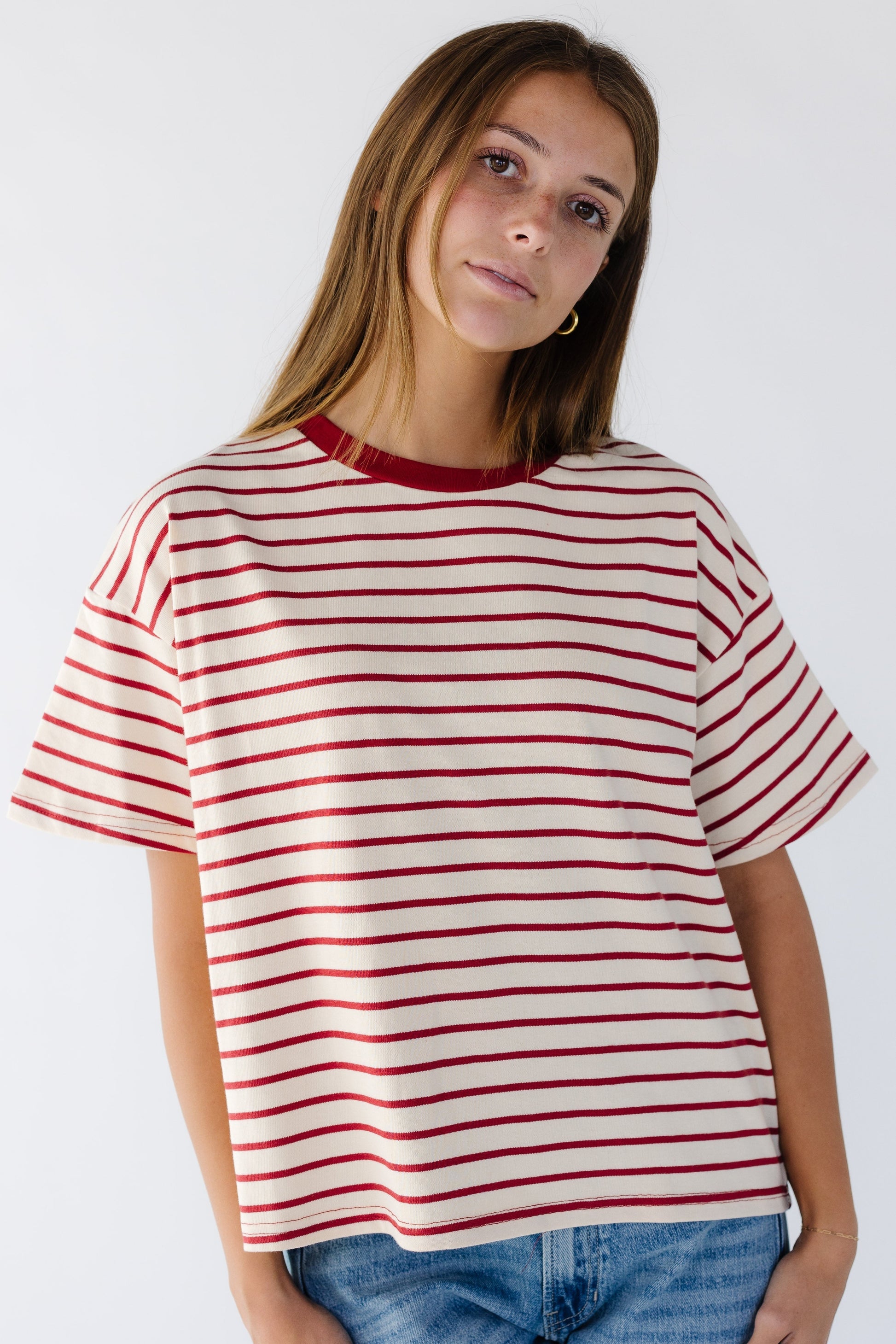 Woman wearing a cream and red stripe loose fitting tee with short sleeves.