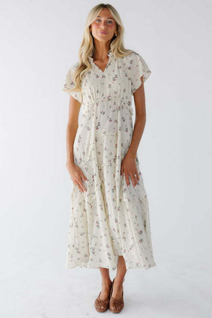 Woman wearing a loose fitting cream and lavender print midi-maxi dress witn an empire waist.