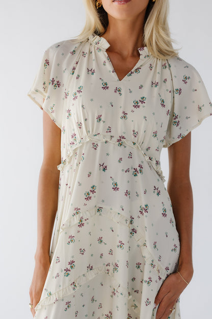 Young woman wearing a cream & lavender floral print midi dress with a curved empire waist, short sleeves and a V-neckline.