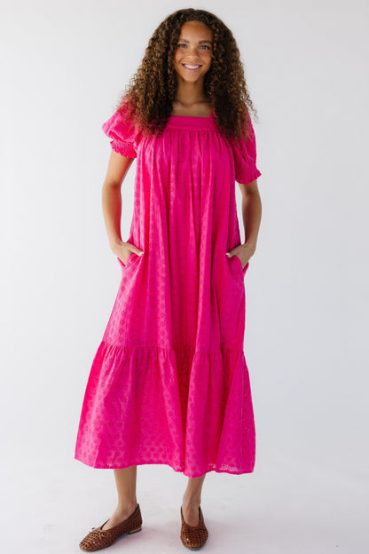 Teenage girl wearing a modest bright pink eyelet midi dress with a square neckline and puff sleeves.