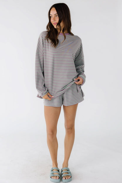 Woman wearing a purple & green stripe shorts set with long sleeves, crew neckline and shorts.
