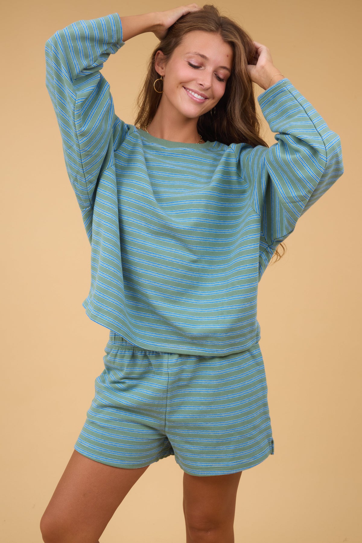 Young woman wearing a green & grey stripe shorts lounge set with a ong sleeve top.