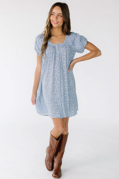 Woman wearing a modest short dress with a scoop neckline and short puff sleeves. 