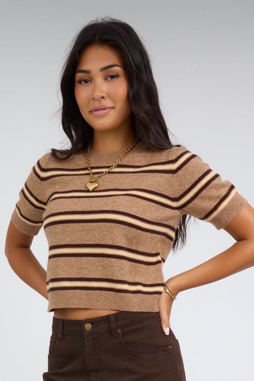 Woman wearing a light brown, short sleeve sweater with brown & yellow stripes and a crew ribbed neckline.