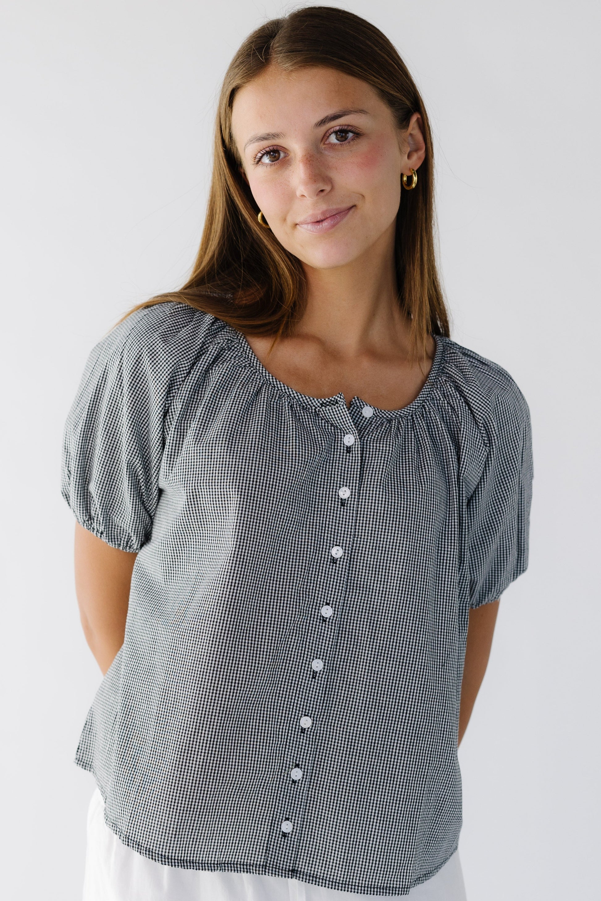 Young woman wearing a modest, loose fitting button down top with a round neckline and short puff sleeves.