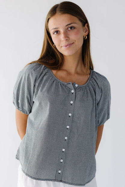 Young woman wearing a modest, loose fitting button down top with a round neckline and short puff sleeves.