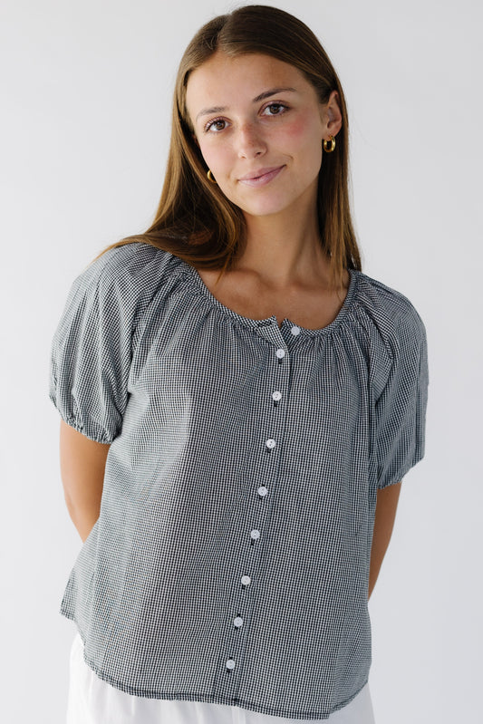 Young woman wearing a modest, loose fitting button down top with a round neckline and short puff sleeves.