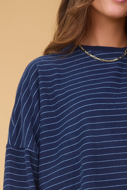 Close view of a woman wearing a navy stripe lounge top with a round neckline and long sleeves.