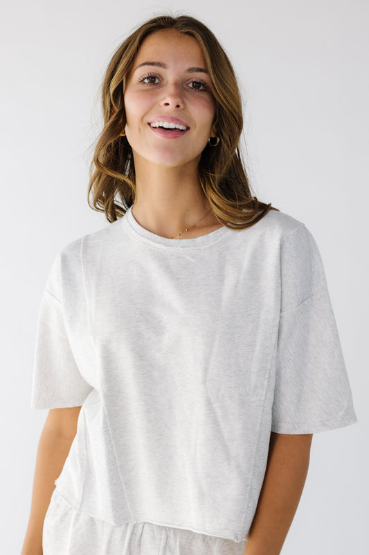 Young woman wearing a ight grey loose fitting tee with elbow length sleeves.