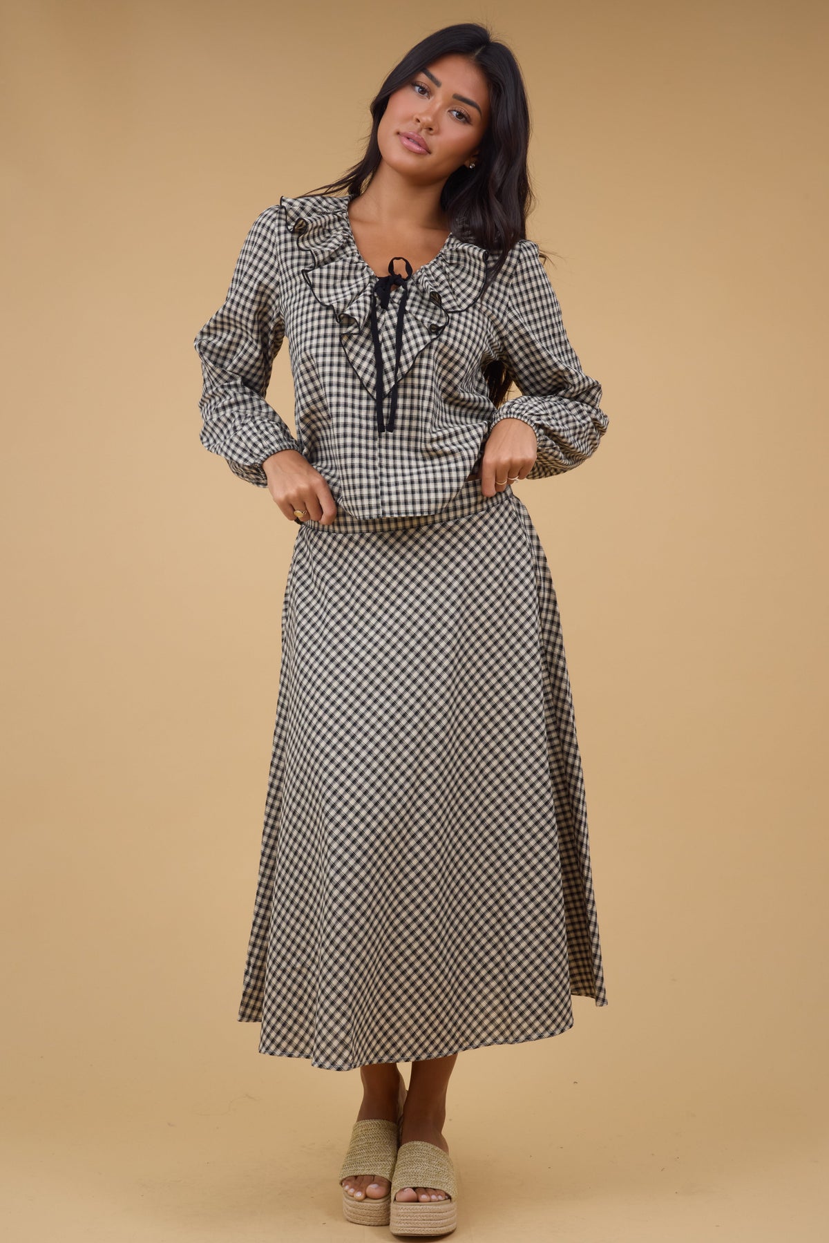 Woman wearing a plaid A-line midi skirt with a mathing long sleeve blouse.