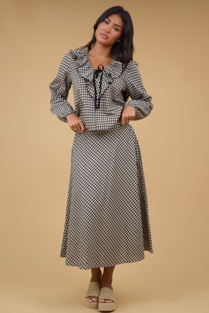 Woman wearing a plaid A-line midi skirt with a mathing long sleeve blouse.