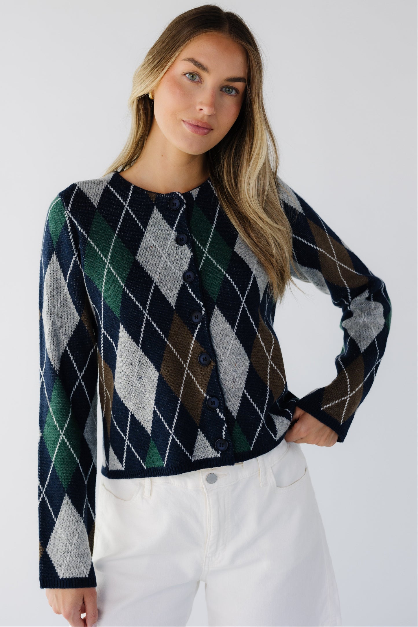 Young woman wearing a modest  navy argyle cardigan with grey, green & brown with a round neckine and long sleeves.