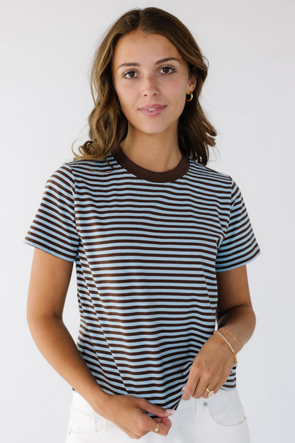 A young woman wearing a brown and blue stripe t-shirt with a crew neckline and short sleeves.