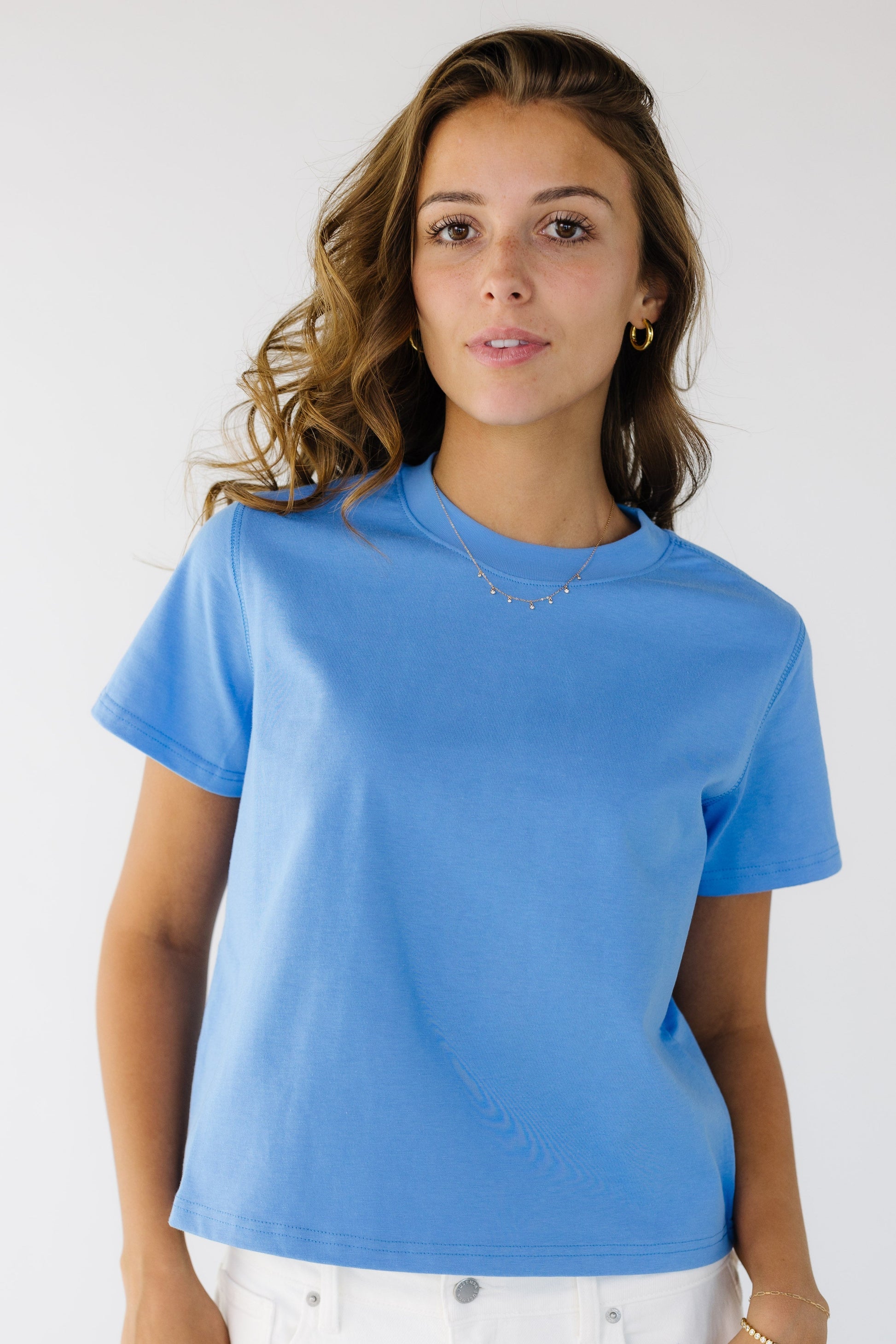 Woman wearing a blue, boxy cut tee with a crew neckline.