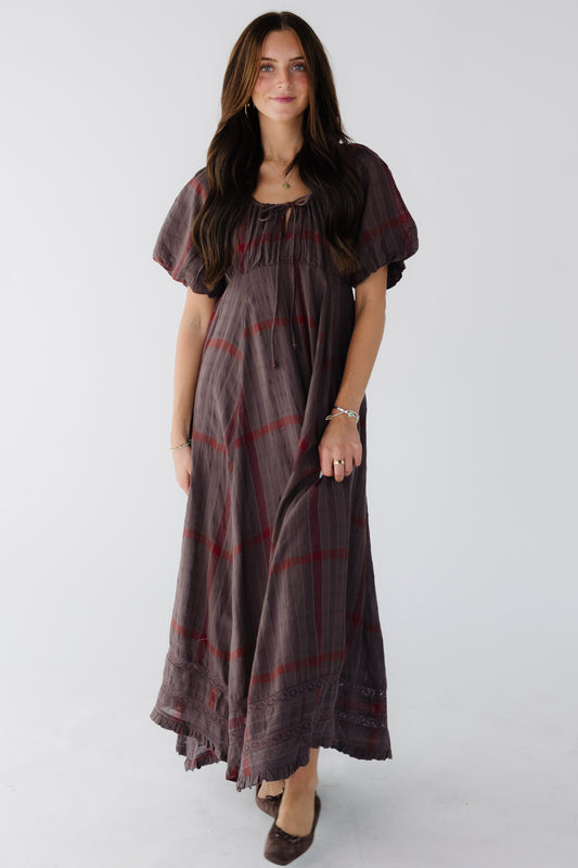 Young woman wearing a modest brown and red plaid midi maxi dress with lace insets near the hem, and empire waist, drawstring-scoop neckline and short balloon sleeves.