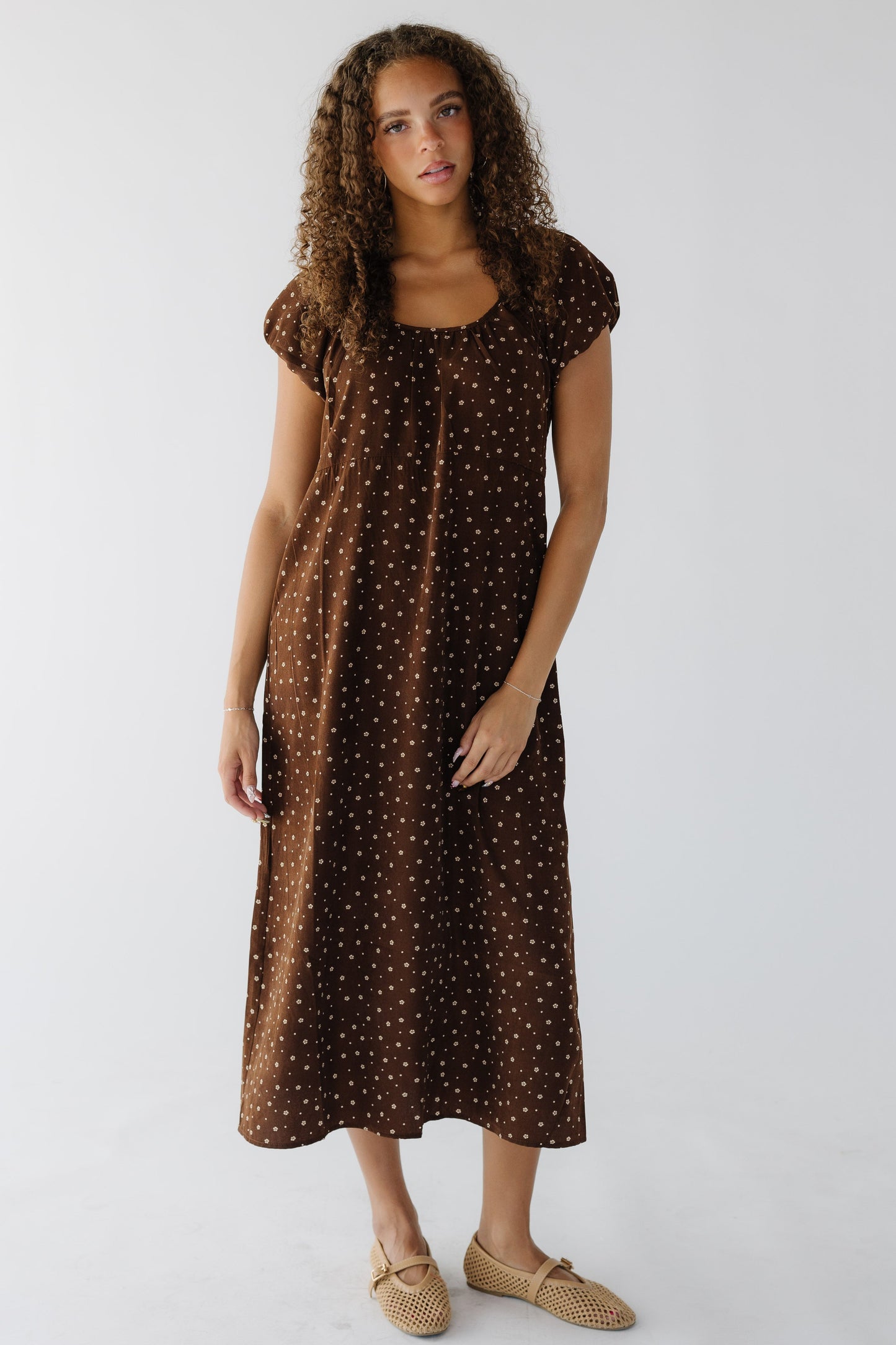Teenage girl wearing a brown midi dress with a scoop neckline and short puff sleeves.