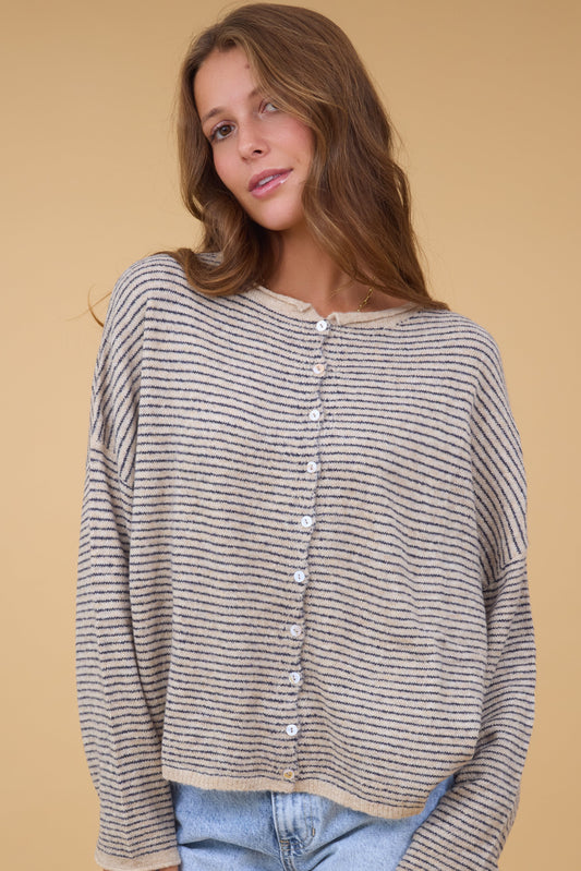 A young woman wearing a modest stripe, button down cardigan with a rolled collar, drop shoulder and long sleeves