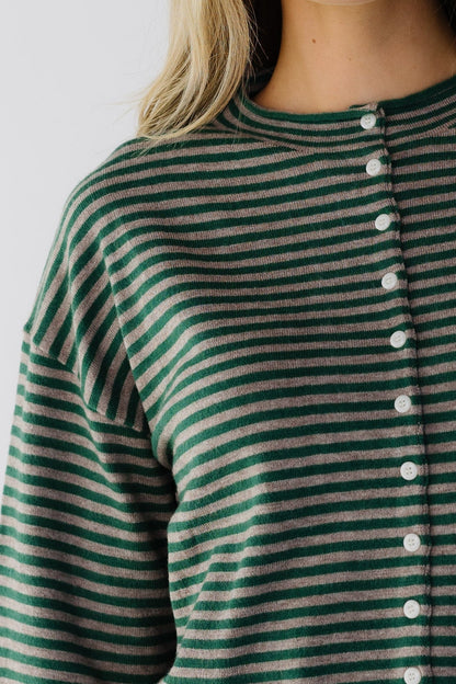 Close view of a woman wearing a taupe & green stripe button down cardigan.