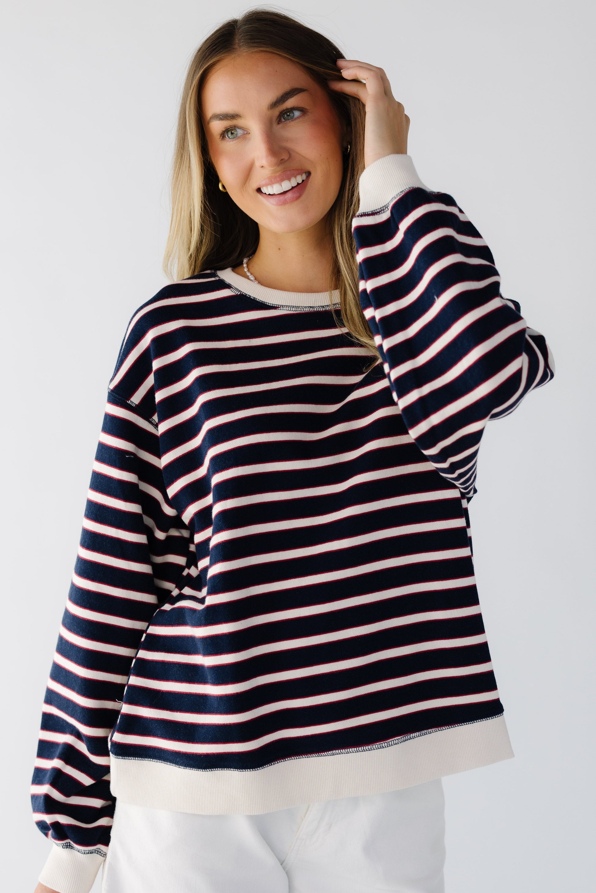 Woman wearing a navy stripe knit top with long cuffed long sleeves.