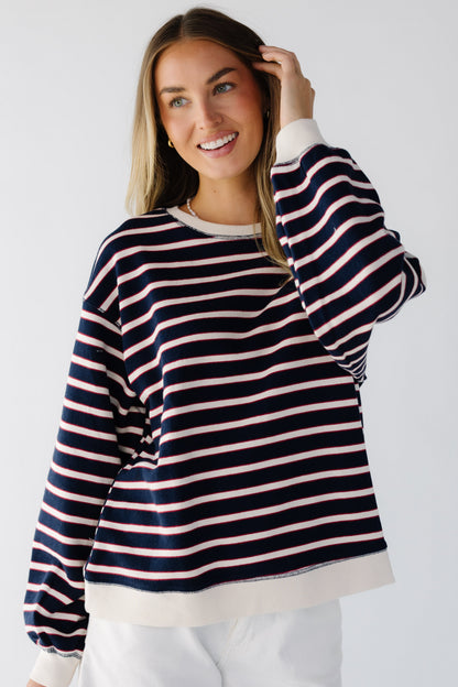 Woman wearing a navy stripe knit top with long cuffed long sleeves.