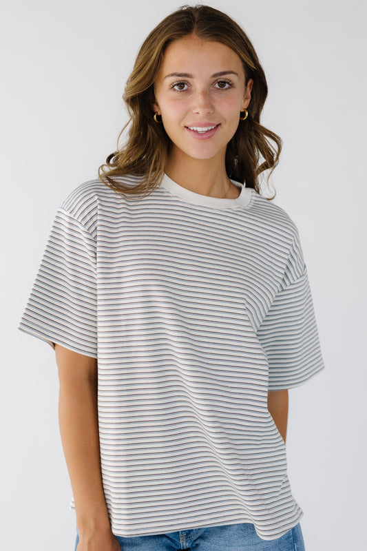 Young woman wearing a white stripe, loose fitting tee with short sleeves and a crew neckline. 