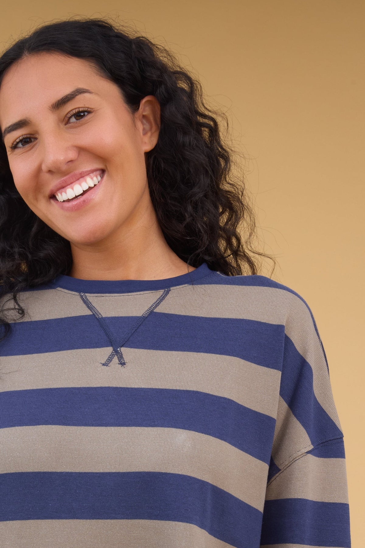 Woman wearing a navy & taupe oversized top with a crew neckline and long sleeves.