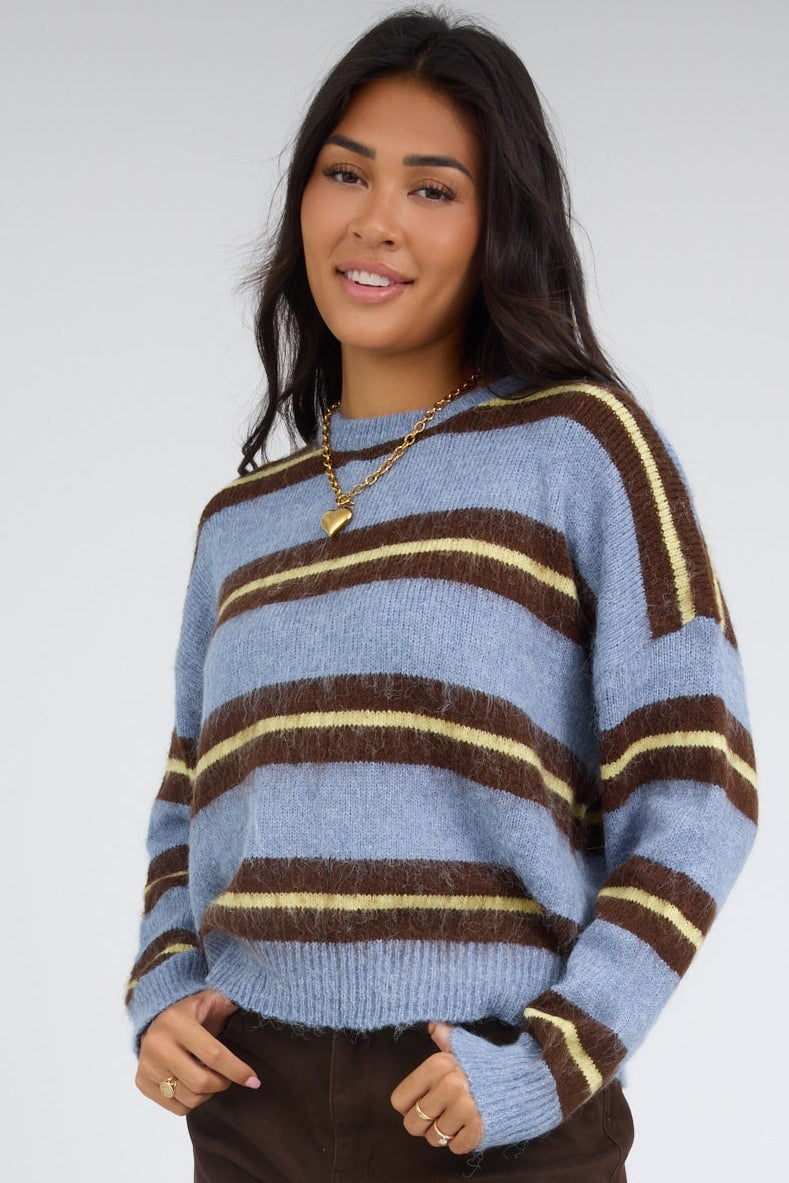 Young woman wearing a loose fitting blue stripe pullover with drop shoulders & long sleeves.
