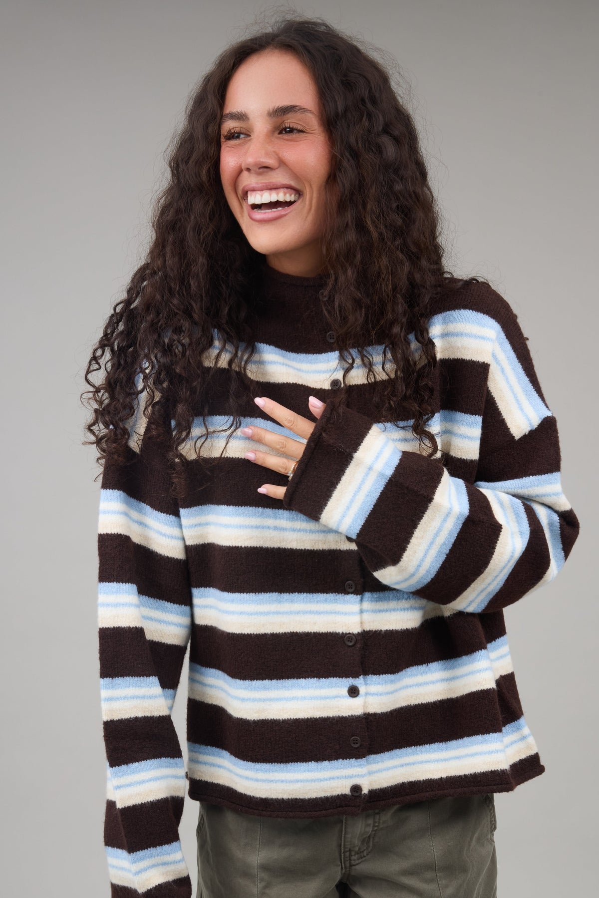 Young woman wearing a modest brown, blue multi stripe cardiganwith long sleeves.