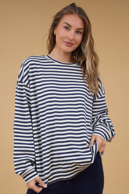 Young woman wearing a modest navy & white stripe oversized top with long sleeves.