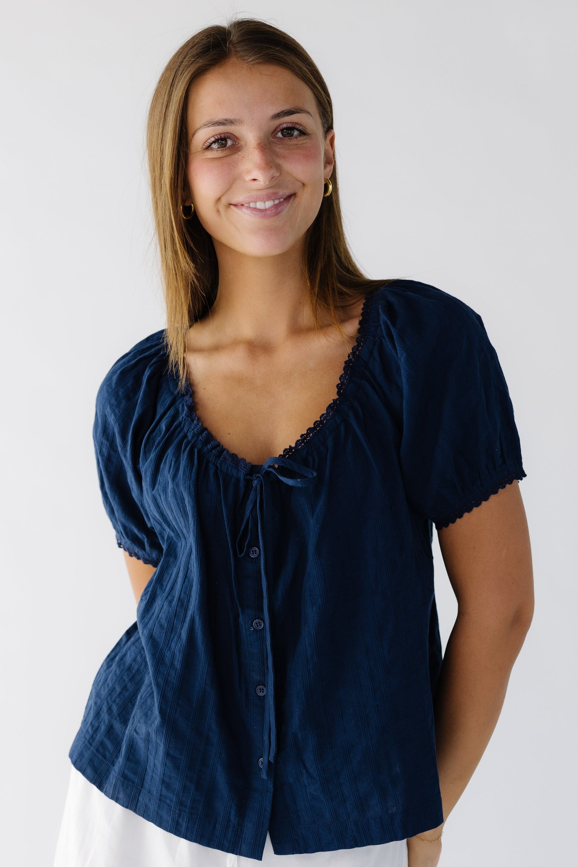 Young woman wearing a modest loose fiting button down blouse with a scoop lace trimmed neckline and short lace trimmed sleeves.