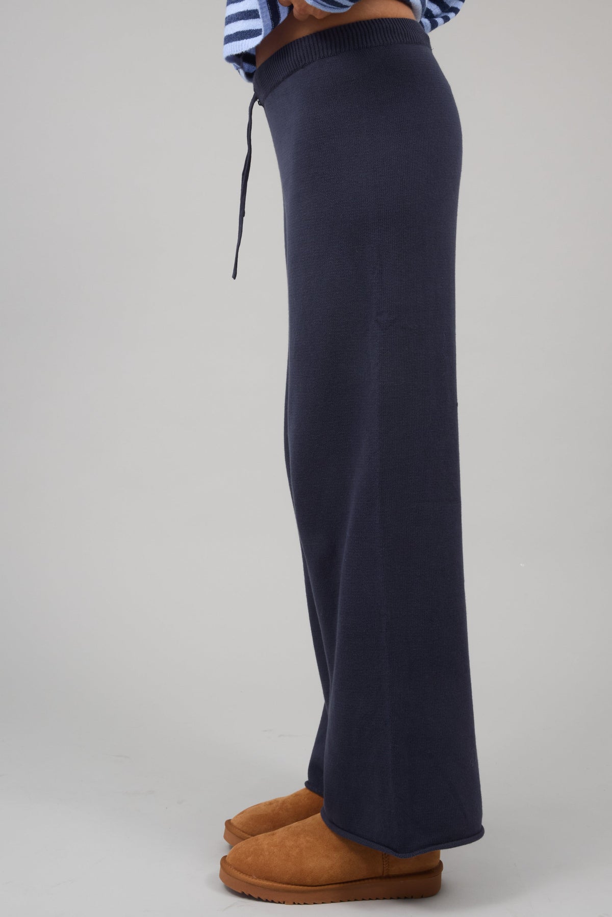 Side view of a woman wearing a pair of navy sweater knit wide leg pants.