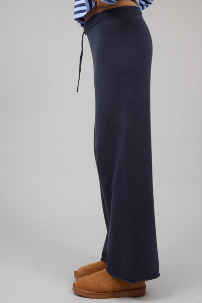 Side view of a woman wearing a pair of navy sweater knit wide leg pants.