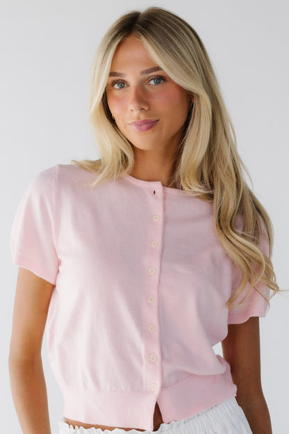 Woman wearing a short sleeve cardigan in pink with short puff sleeves.