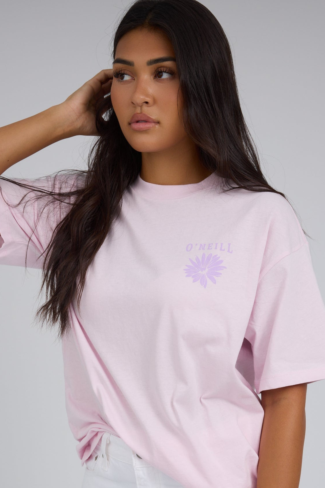 Young woman wearing a modest light pink short sleeve tee with a small front graphic.