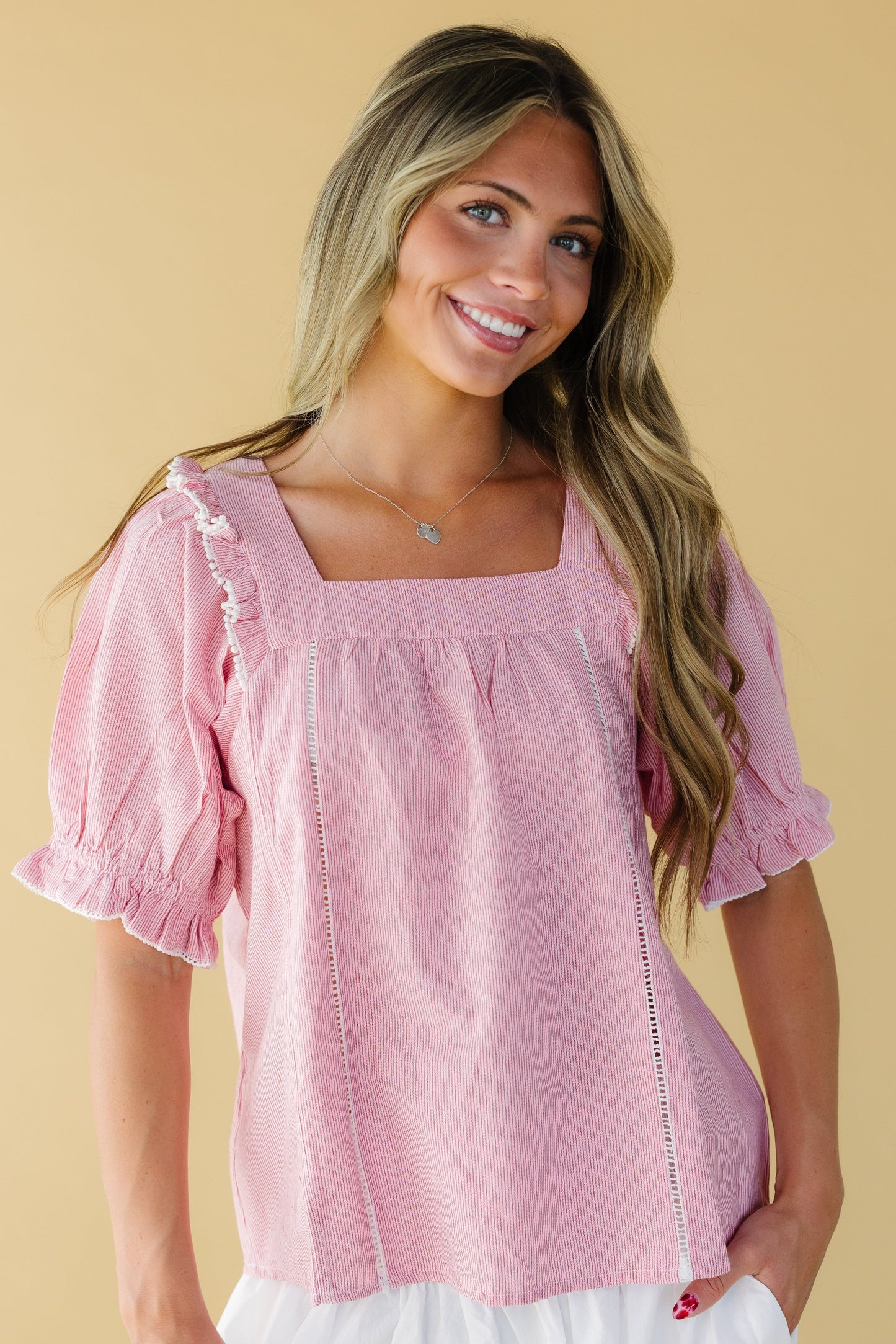 Young woman wearing a red & white stripe blouse with a square neckline, ladder lace insets and elbow length puff sleeves.
