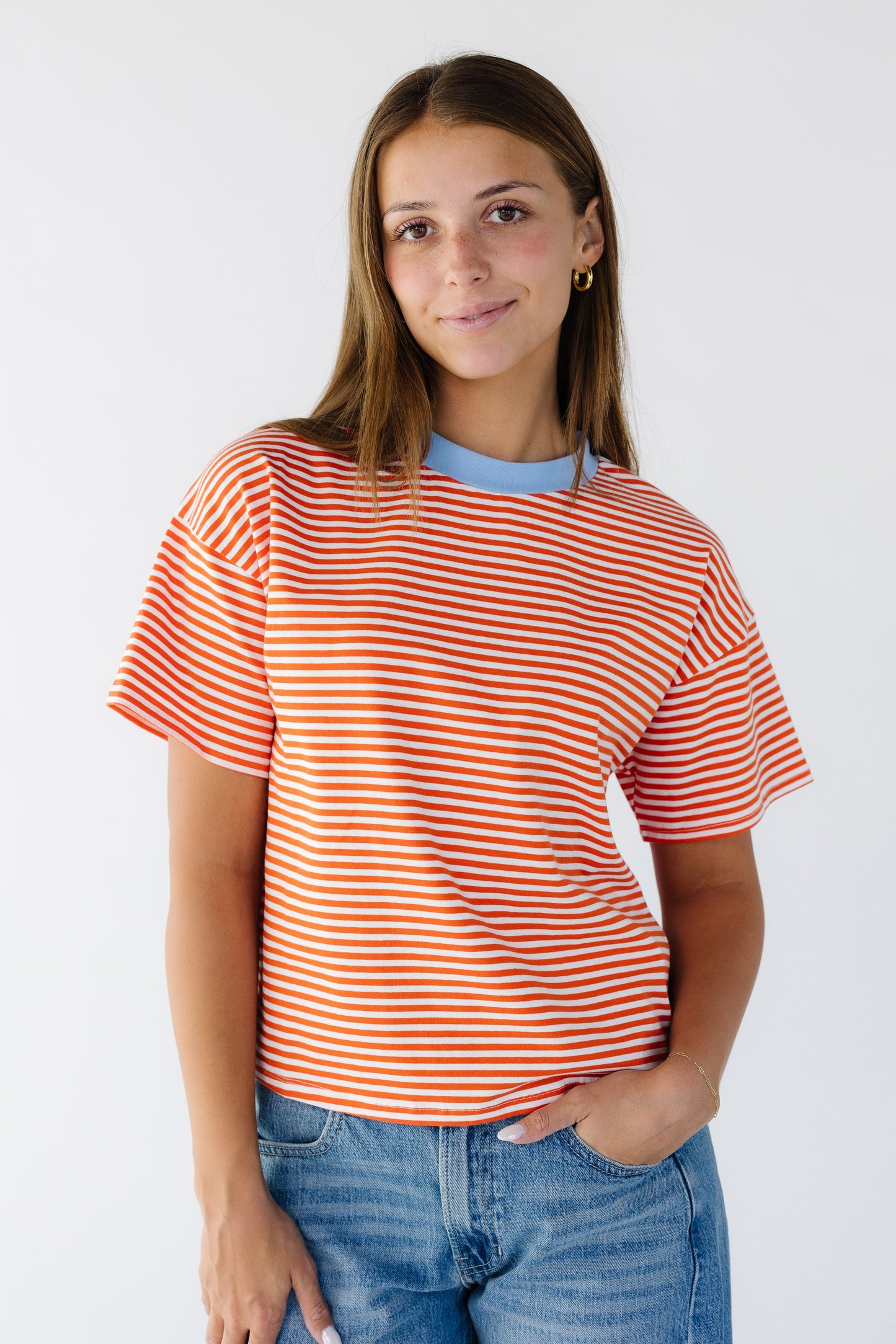 Woman wearing a modest white and orange stripe tee with a contrasting crew neckline.