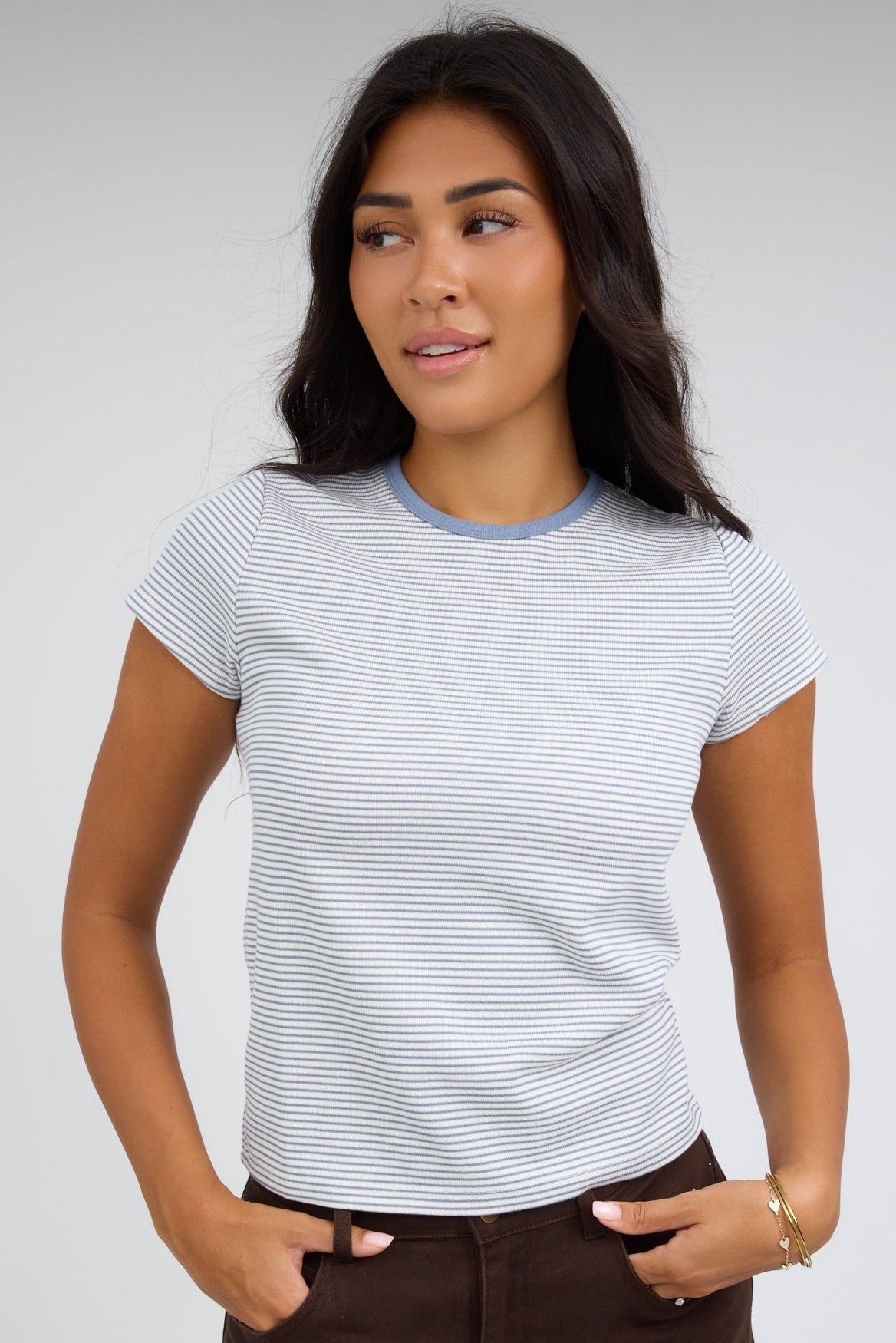Woman wearing a white & blue stripe close fittig tee with a round neckline and short sleeves.