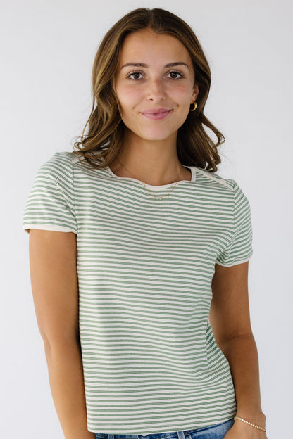 Young woman wearing an closer fitting knit top in ivory and double green stripes with short sleeves and a round trimmed neckline. 
