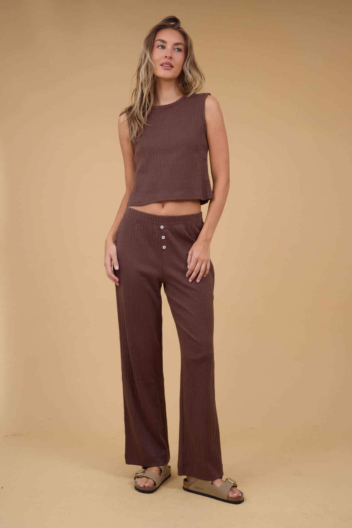 A young woman wearing a pair of wide leg brown pointelle pants with a matching Soft Knit Pointelle Knit Tank.
