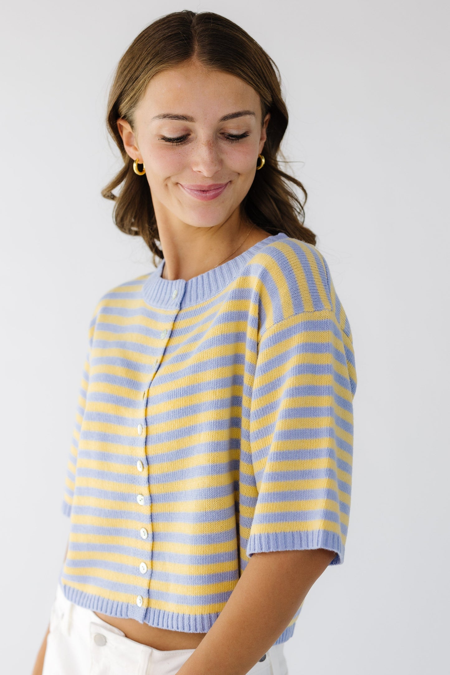 Young woman wearing a modest button down cardigan with short sleeves in light blue and yellow stripe.