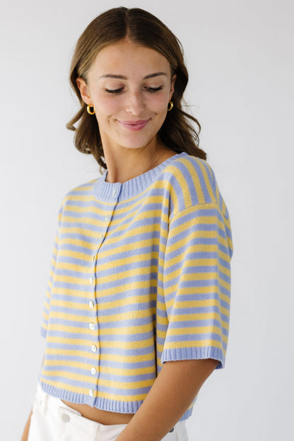 Young woman wearing a modest button down cardigan with short sleeves in light blue and yellow stripe.