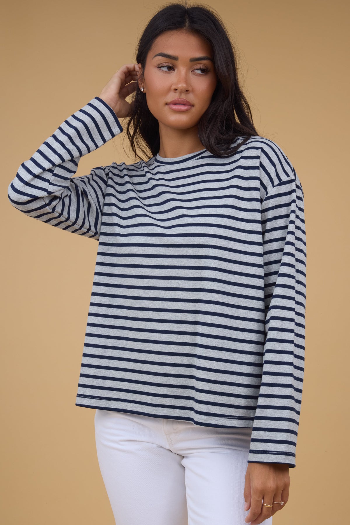Young woman wearing a modest grey & navy stripe top with a crew neckline and long sleeves.